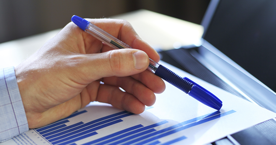 Close-up of hand holding a pen on a piece of paper with a graph